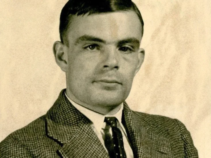 Svartvitt porträtt av Alan Turing i tweedkavaj och slips, taget 1936 vid Princeton University